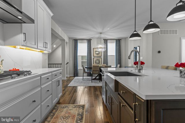 a kitchen with stainless steel appliances kitchen island granite countertop a refrigerator a stove and a sink with wooden floor