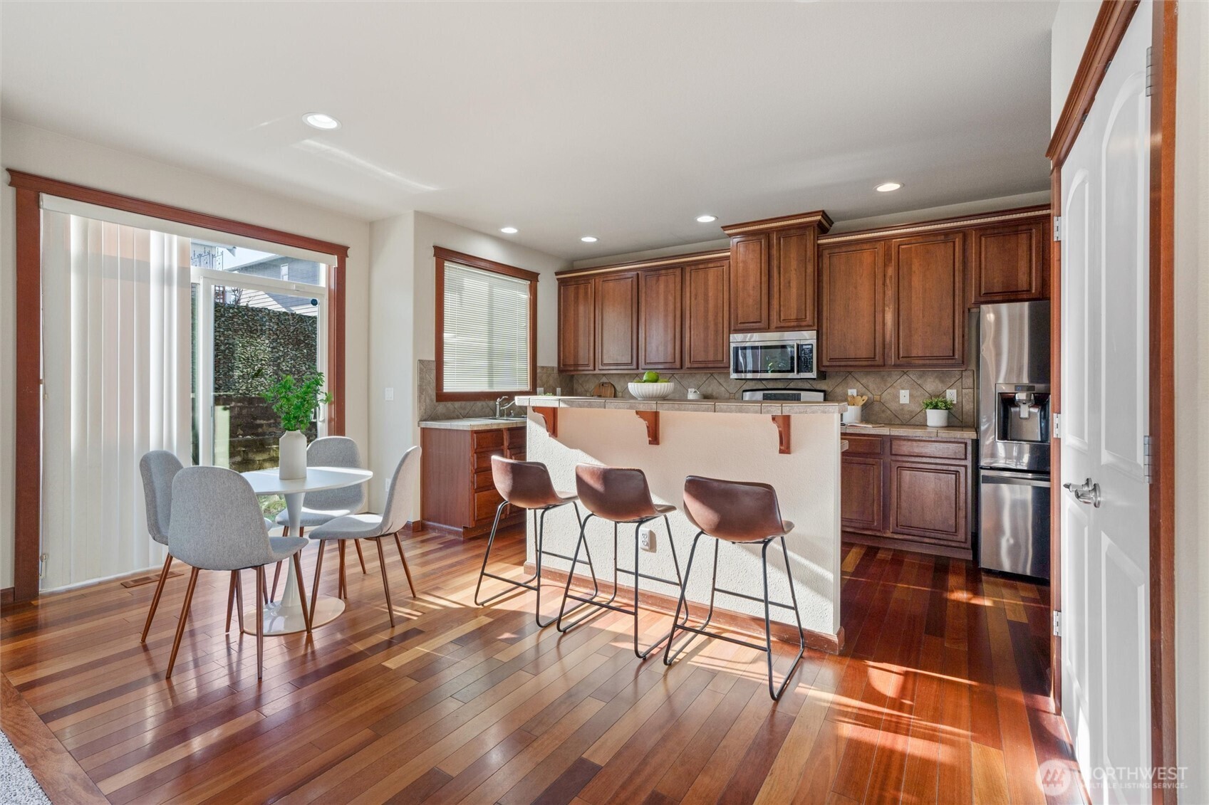 9432 202nd Street East Graham, WA 98338 - Photo 9 of 35 a kitchen with stainless steel appliances granite countertop a stove top oven a refrigerator a dining table and chairs with wooden floor