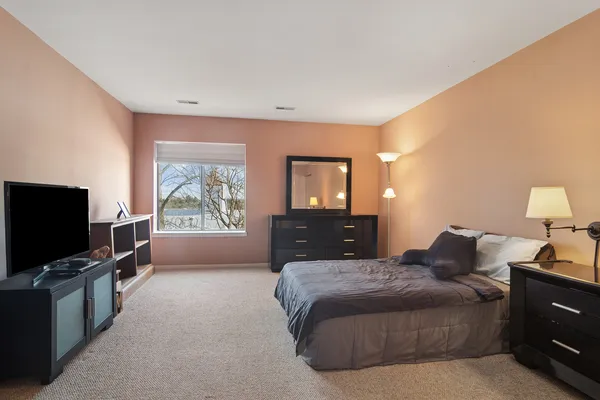 a spacious bedroom with a bed and a flat screen tv