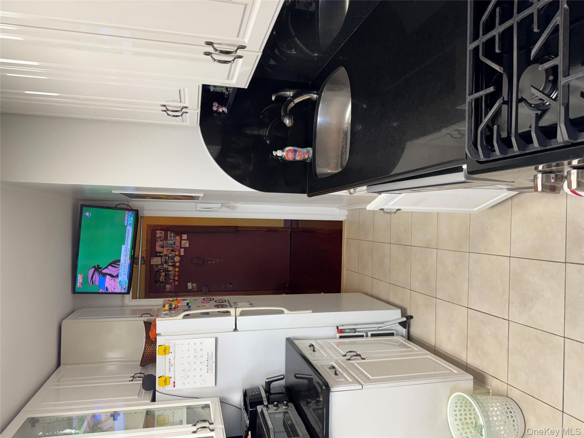 220-55 46th Avenue, Unit 10D Queens, NY 11361 - Photo 11 of 32 Kitchen with white cabinets, light tile patterned floors, fridge, and glass insert cabinets
