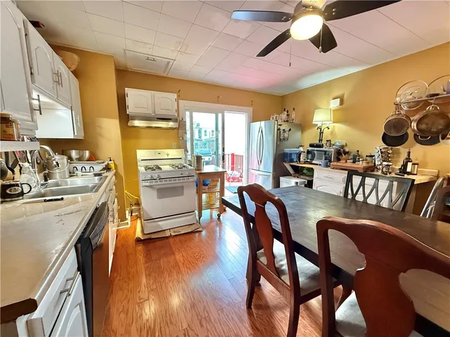 a kitchen with stainless steel appliances granite countertop a stove a sink a dining table and chairs with wooden floor