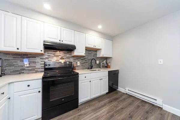 a kitchen with granite countertop white cabinets and black appliances