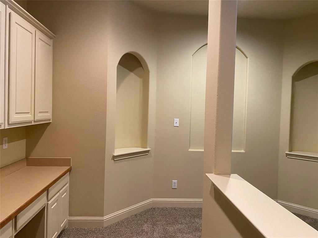 2222 Kirby Street Dallas, TX 75204 - Photo 13 of 25 Built-in desk area featuring upper and lower cabinetry, a light-toned countertop, and carpet flooring