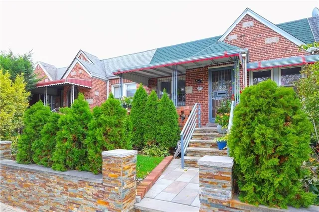 a front view of a house with a yard and potted plants