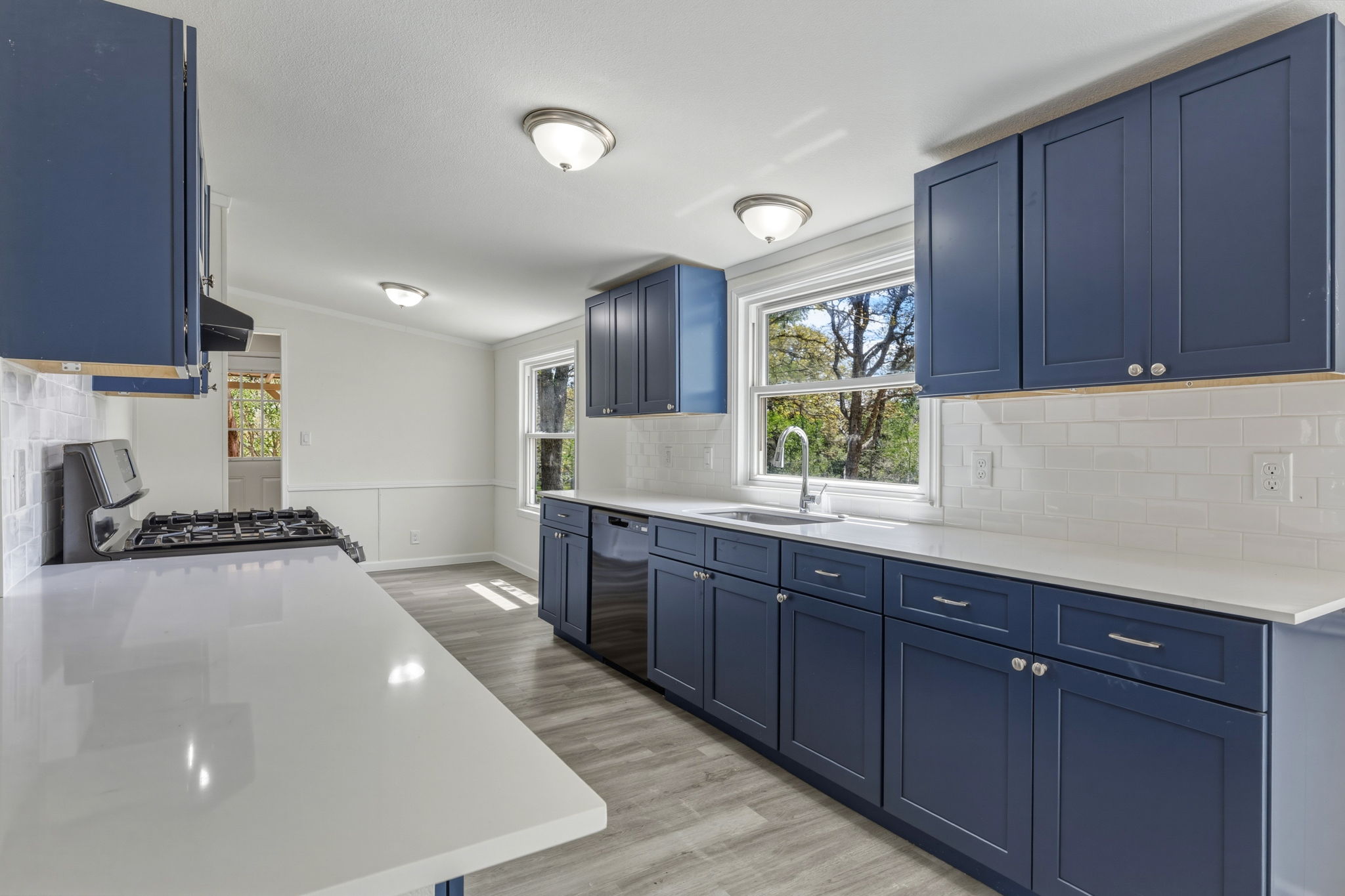 340 Red Hawk Drive Dale, TX 78616 - Photo 16 of 39 Kitchen featuring blue cabinets, backsplash, range and range hood, light colored floors, and quartz countertops,