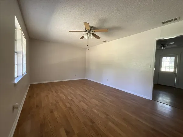 an empty room with wooden floor and windows