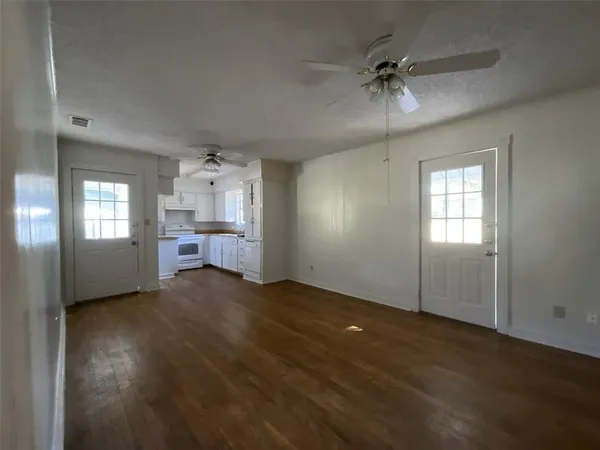 a view of an empty room with a window and a kitchen