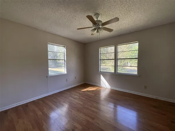 a view of empty room with wooden floor and fan