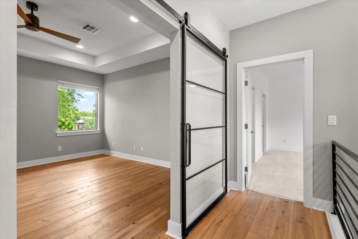 913 Stobaugh Street, Unit B Austin, TX 78757 - Photo 29 of 40 A sliding glass door separates a sun-filled room from a hallway with warm hardwood floors.