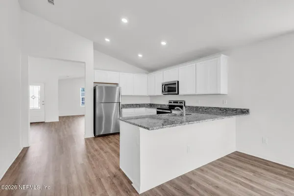 a kitchen with stainless steel appliances granite countertop a refrigerator and a stove top oven