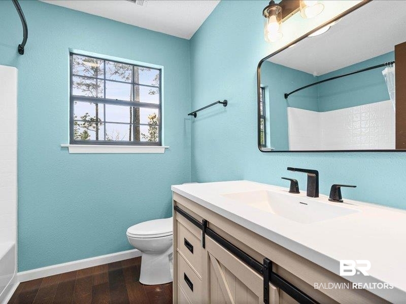 3160 Old Castleberry Road Brewton, AL 36426 - Photo 16 of 36 Bathroom featuring a barn door style vanity with a white countertop, matte black fixtures, an integrated sink, and wood-finish flooring
