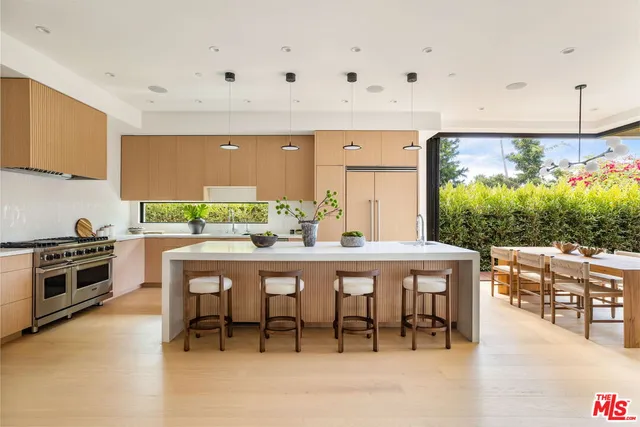 a dining area with stainless steel appliances a white table and chairs in it