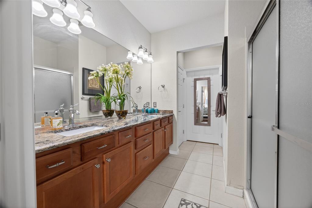 9106 Southwest 65th Loop Ocala, FL 34481 - Photo 12 of 38 a bathroom with a granite countertop sink a mirror and a shower