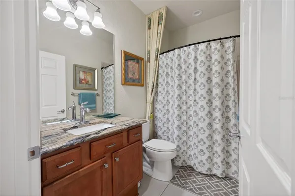 a bathroom with a granite countertop sink a toilet and a shower