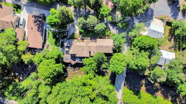 655 Ogden Canyon Road Ogden, UT 84401 - Photo 39 of 50 Aerial perspective showcasing a property surrounded by mature trees, featuring a brown shingle roof and a multi-level deck overlooking a natural creek