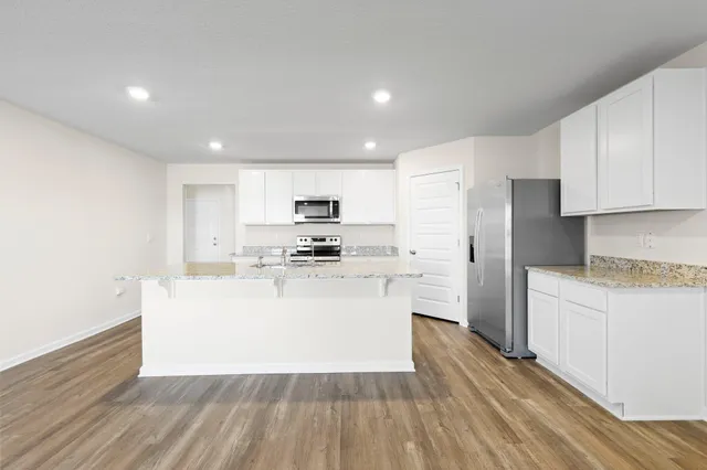 a view of kitchen with stainless steel appliances refrigerator stove microwave and cabinets