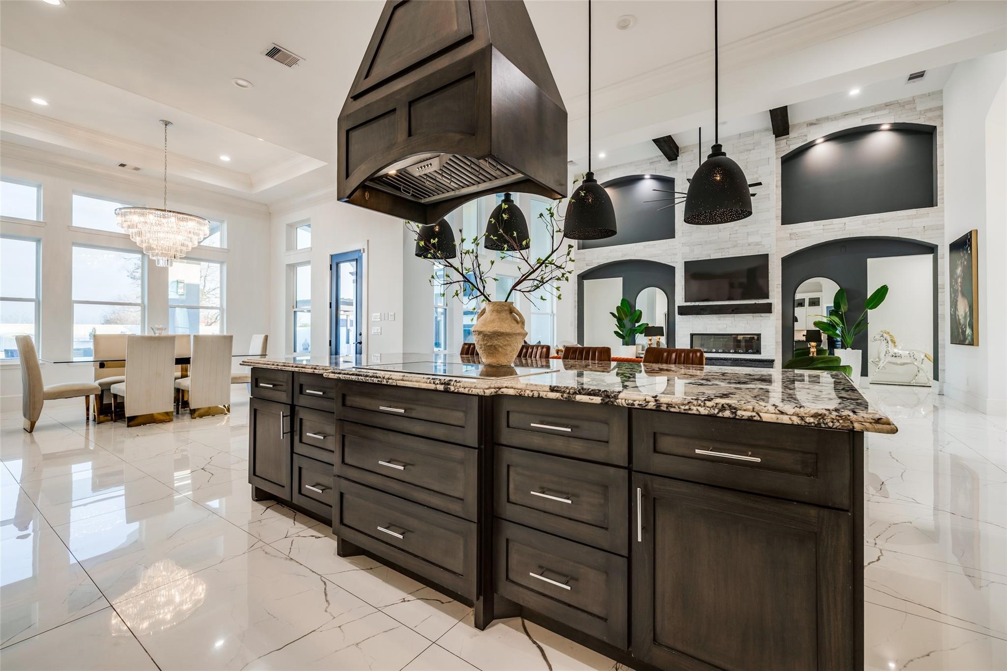 4821 Walters Road Richmond, TX 77469 - Photo 25 of 50 his designer gourmet kitchen makes a bold statement with soaring custom cabinetry, dramatic ceiling-height finishes, and an oversized waterfall island perfect for entertaining. Featuring premium stainless steel appliances, elegant pendant lighting, marble-style flooring, and rich contrasting accents, the space blends timeless sophistication with modern functionality. The open-concept layout, expansive prep areas, built-in wine storage, and abundant natural light create a luxurious culinary experience