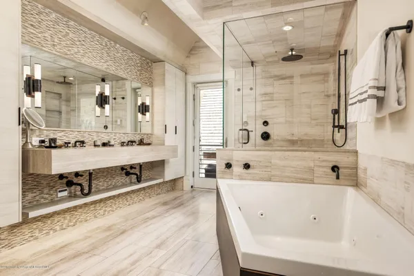a bathroom with a tub a sink and a mirror