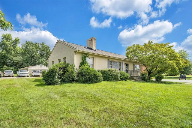 a view of a house with a big yard plants and large trees