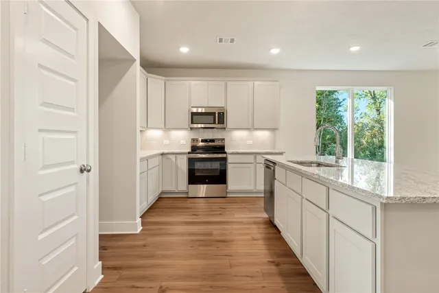 a kitchen with kitchen island a stove a sink and a refrigerator with wooden floor