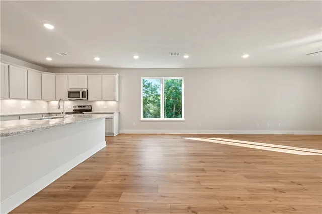 a kitchen with stainless steel appliances granite countertop a stove a sink and a microwave