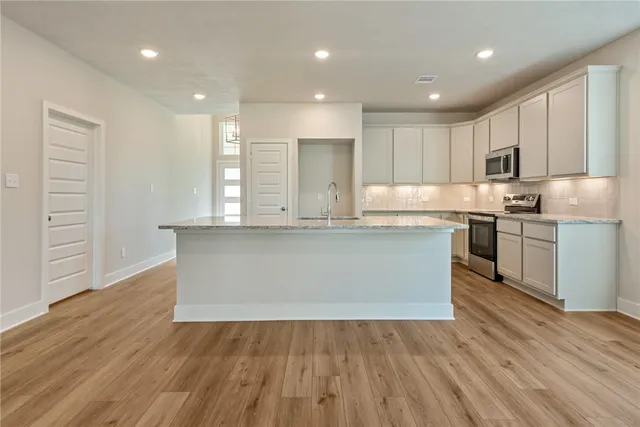a large kitchen with wooden floors and stainless steel appliances