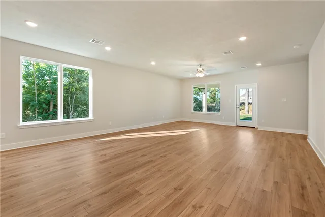 an empty room with wooden floor and windows