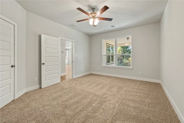 an empty room with windows and a ceiling fan