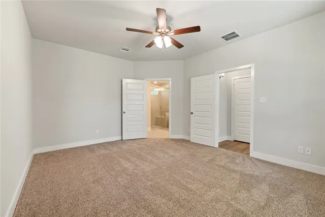 an empty room with closet and ceiling fan