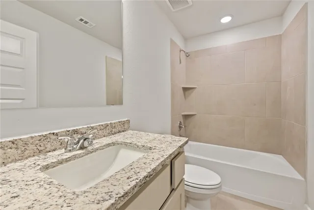 a bathroom with a granite countertop sink a toilet and bathtub