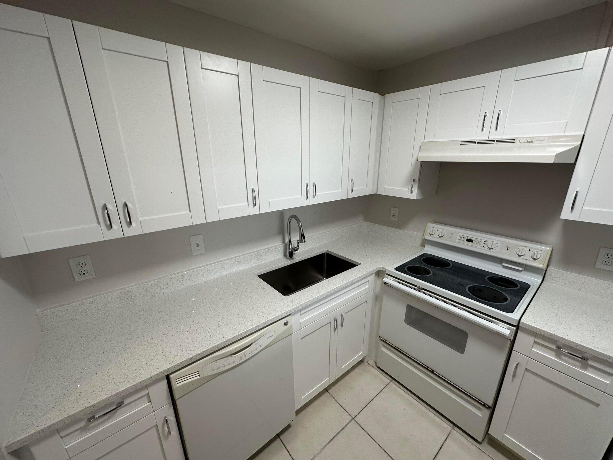 9355 Southwest 8th Street, Unit 421 Boca Raton, FL 33428 - Photo 6 of 20 a kitchen with white cabinets and white appliances