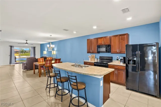a kitchen with stainless steel appliances granite countertop a table chairs sink refrigerator and granite counter tops