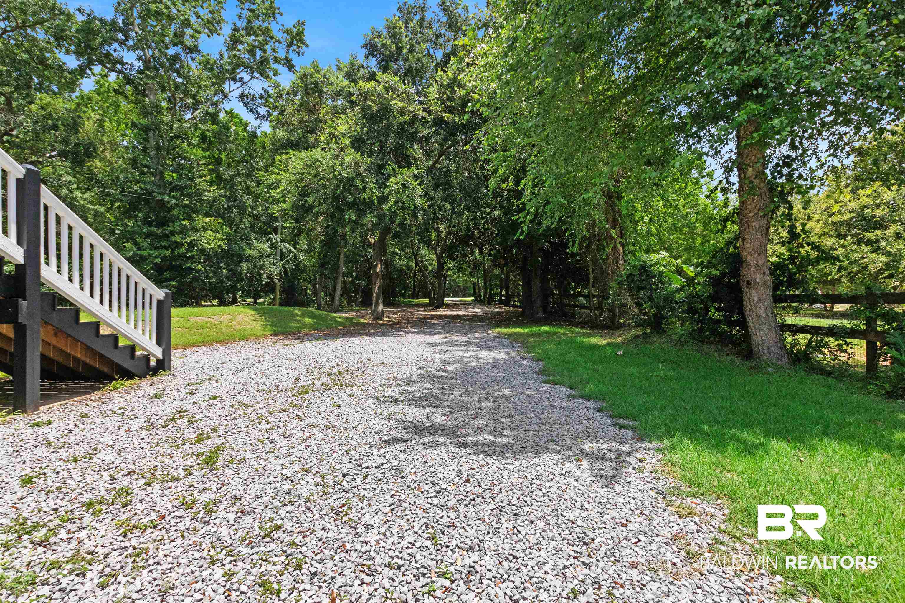 9581 South Bay Street Foley, AL 36535 - Photo 7 of 44 Gravel driveway framed by mature trees and natural landscaping