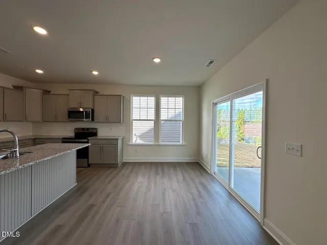 a large kitchen with a large counter top a sink stainless steel appliances and cabinets