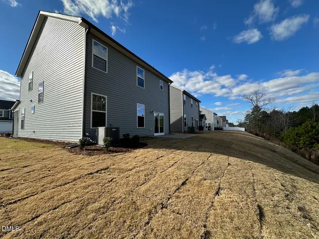 a view of house with backyard and trees in the background