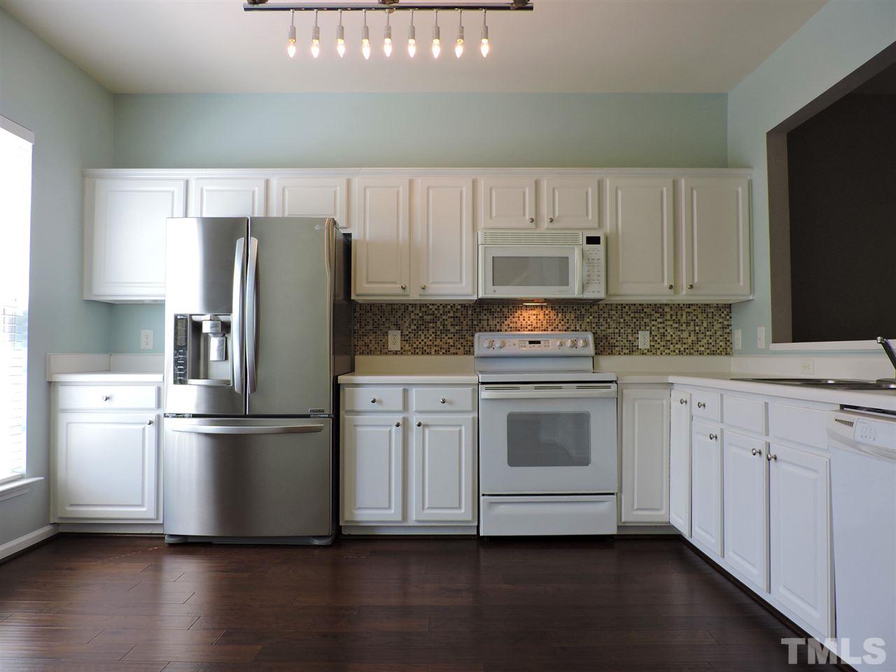 7242 Janston Drive Raleigh, NC 27613 - Photo 3 of 24 a kitchen with a refrigerator stove and wooden cabinets