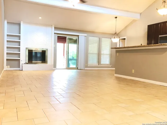 a view of an empty room with a fireplace and a window