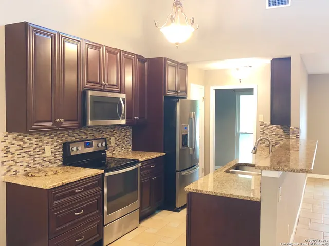 a kitchen with granite countertop cabinets stainless steel appliances and a counter space