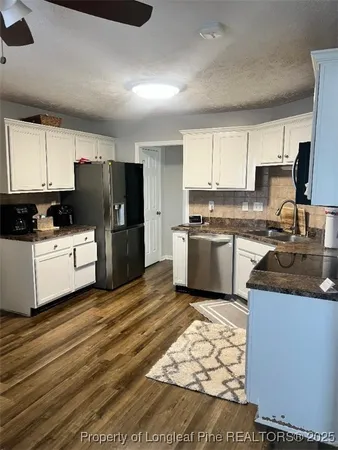 a kitchen with a sink a refrigerator a microwave and cabinets