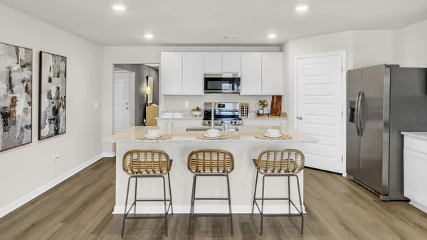 a kitchen with stainless steel appliances granite countertop a dining table chairs refrigerator and microwave