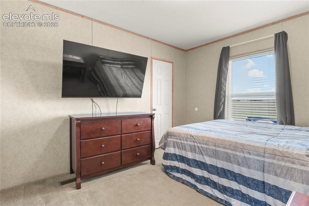 22280 Jones Road Peyton, CO 80831 - Photo 27 of 47 a bedroom with a bed and a flat screen tv