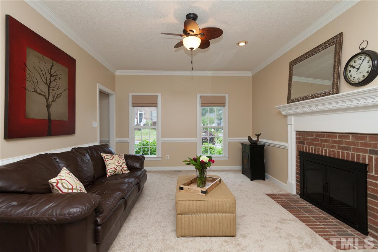 124 Huntsmoor Lane Cary, NC 27513 - Photo 3 of 25 a living room with furniture a clock and a fireplace