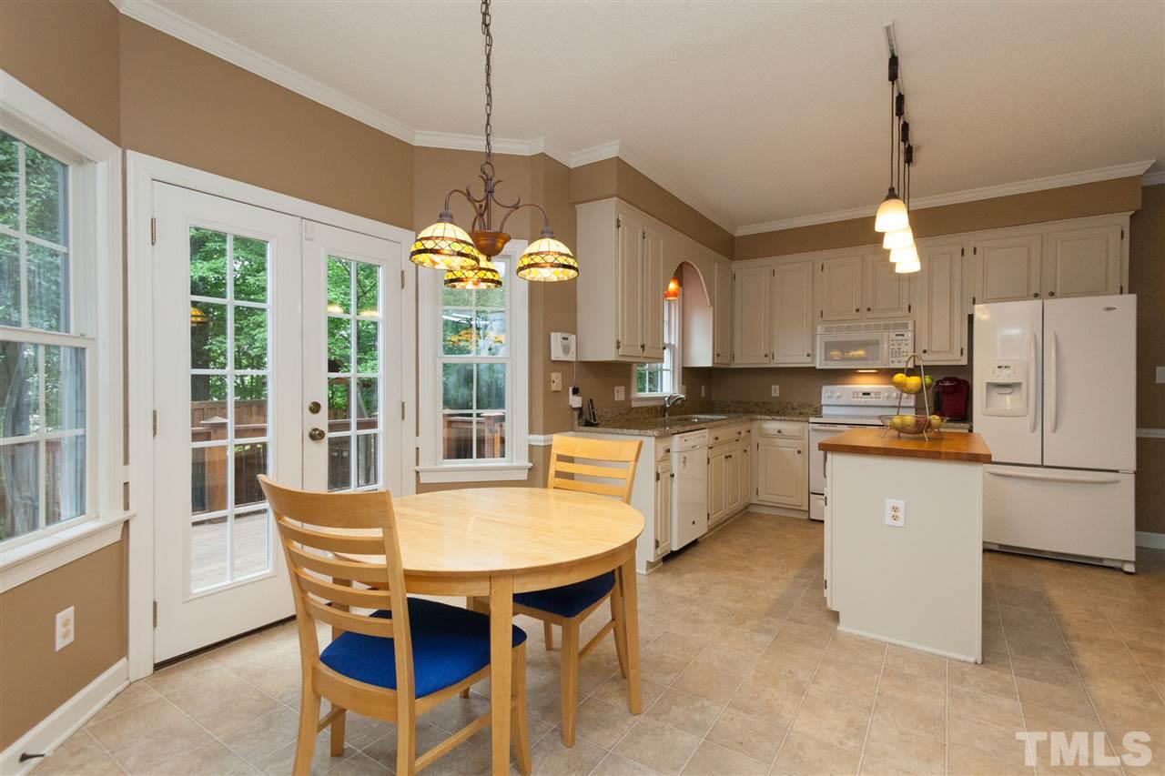 124 Huntsmoor Lane Cary, NC 27513 - Photo 7 of 25 a kitchen with stainless steel appliances granite countertop a stove a refrigerator a sink dishwasher a dining table and chairs with wooden floor