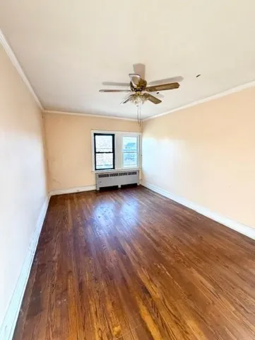 an empty room with wooden floor chandelier fan and windows