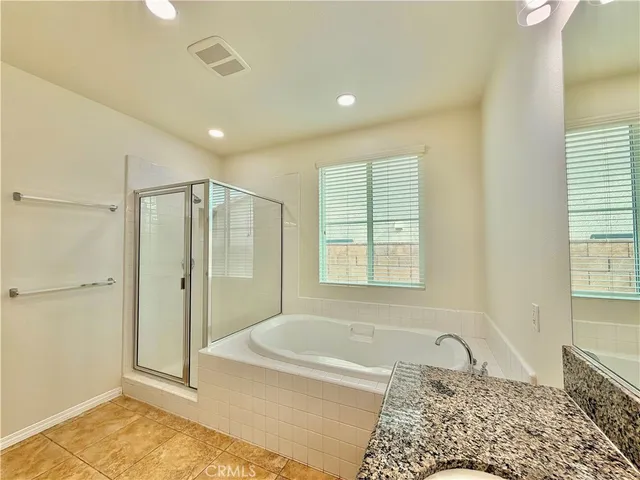 a bathroom with a granite countertop tub shower and closet