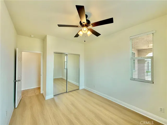 a view of empty room with wooden floor and fan