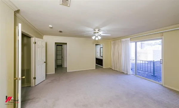 an empty room with chandelier fan and bathroom