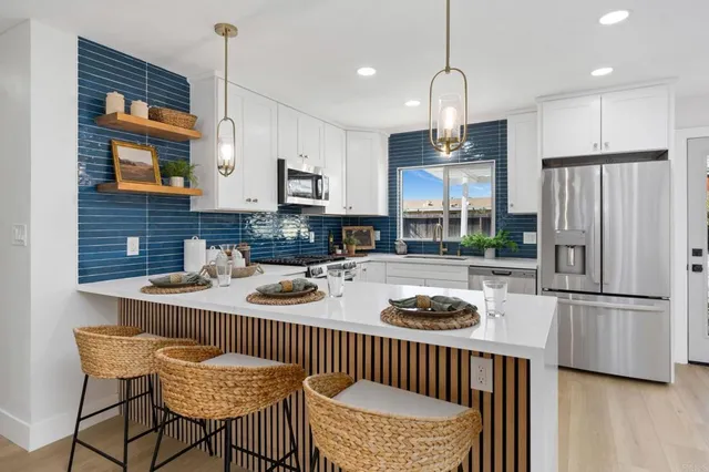 a kitchen with stainless steel appliances granite countertop a sink a stove a refrigerator cabinets and a dining table