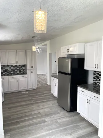 a kitchen with granite countertop a refrigerator and a stove top oven