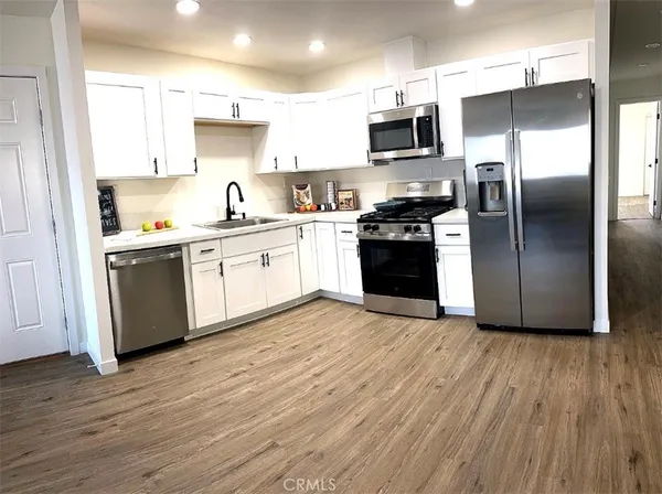 a kitchen with granite countertop a refrigerator and a stove top oven